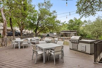 A wooden deck with a table and chairs and a grill.